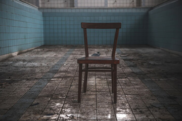 Fototapeta na wymiar Old wooden chair in an abandoned pool. Old broken furniture. Abandoned pool. Blue tiles.