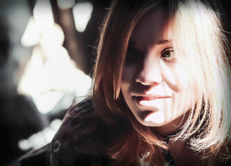Fototapeta na wymiar Contrast Sunlight and Shadows on the Face of a Smiling Young Blonde Woman