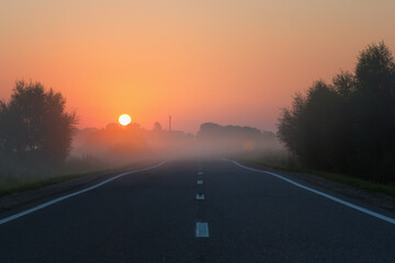 Empty Road Leading to Golden Sunrise on Foggy Morning - 480511990