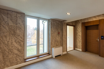 Interior of a carpeted hotel corridor doorway with brown wooden doors