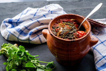 a pot with vats of greens and a towel on a dark background