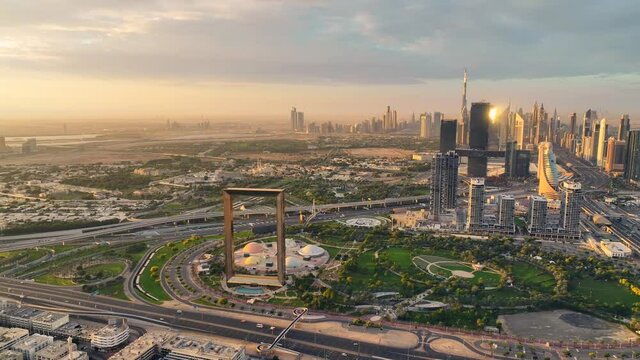 Aerial View of Dubai Frame shining during dramatic sunrise with futuristic city skyline in the back