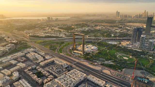 Aerial View of Dubai Frame shining during dramatic sunrise with futuristic city skyline in the back