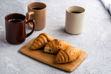 three mugs of coffee and croissants on the table