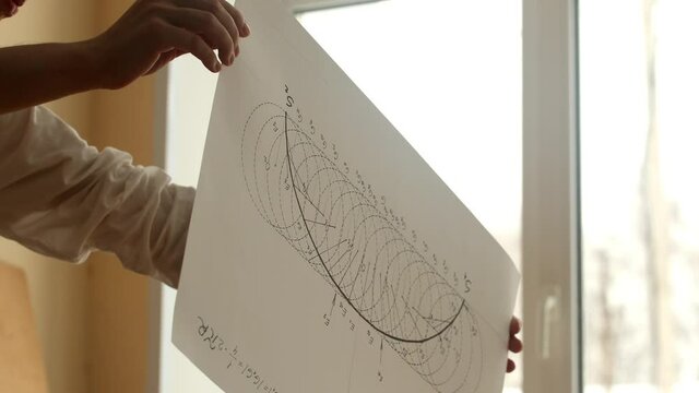 Young mathematician and artist Pavel Kubarkov shows paper with inverted arc of cycloid curve. Date of shooting day 29 December 2021 year, MSK time. This video was filmed in Russia.