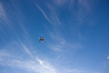 Naklejka na ściany i meble Small drone flying at sunset through a clear sky.