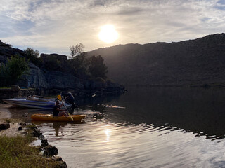 Woman kayaking on a still dam at sunrise