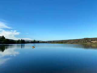 Woman kayaking on a still dam at sunrise