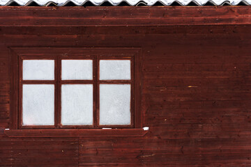 Brown wall of a wooden residential building. There is a three-section window with white frosted glass. Background. Texture.