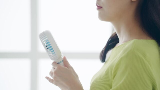 ハンディファンを使う女性　ポータブル扇風機