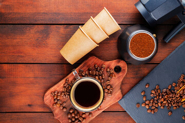 Coffee cup, geyser coffee maker and roasted coffee beans on a wooden background. Ground coffee for making of coffee drinks. Copy space. Top view