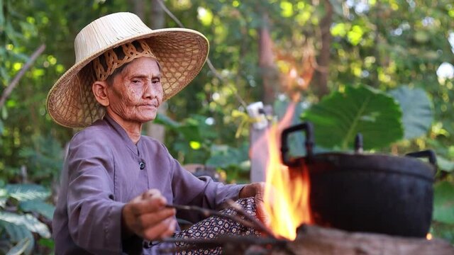 An old woman lighting a cooking fire