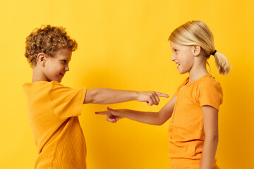 cheerful children in yellow t-shirts standing side by side childhood emotions yellow background unaltered