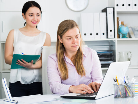 Woman manager supervising work of new female worker in office