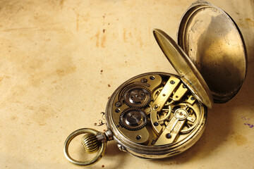 Vintage antique pocket watch on old paper. Clockwork old mechanical watch