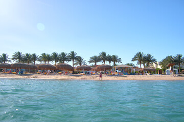 Tourists having fun relaxing on summer beach near warm sea water on tropical resort