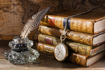 Antique table with books, pen, inkwell and pocket watch. Old map on background. Concept on the...