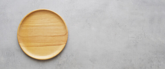 Empty round wooden plate on gray cement table background, banner with copy space, Blank wood tray for food display montage, template, mock up, top view, flat lay