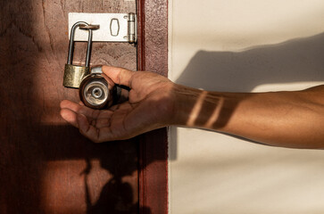 A close-up view of a hand holding a doorknob trying to open i.