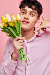 portrait of a young man in a pink shirt with a bouquet of flowers gesturing with his hands Lifestyle unaltered