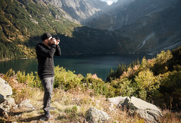 Young  man photographer taking photographs with digital camera in a mountains.