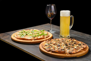Two pizzas and a glass of beer and red wine on a table