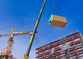 Crane lifting a prefabricated wooden building module to its position in the building. Construction...