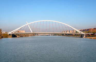 Panoramic view of Barqueta Bridge, a tied arch bridge which spans the Alfonso XIII channel of the Guadalquivir river in Seville, Andalusia, Spain.