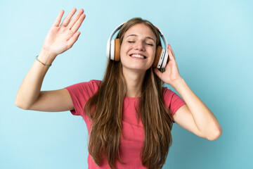 Naklejka premium Young caucasian woman isolated on blue background listening music and dancing