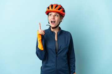 Young cyclist woman isolated on blue background thinking an idea pointing the finger up - obrazy, fototapety, plakaty