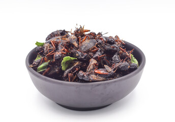 Fried insects, fried crickets with grasshoppers and kaffir lime leaves in a black cup with separate servings on a white background