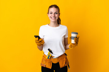 Young electrician woman isolated on yellow background holding coffee to take away and a mobile