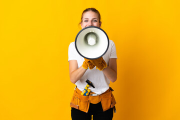 Young electrician woman isolated on yellow background shouting through a megaphone - obrazy, fototapety, plakaty