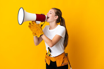 Young electrician woman isolated on yellow background shouting through a megaphone