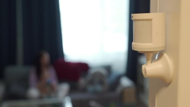 Smart home wireless motion sensor installed on the wall of the living room, motion detector used to detect activities like movement and control smart lights. High quality 4k footage