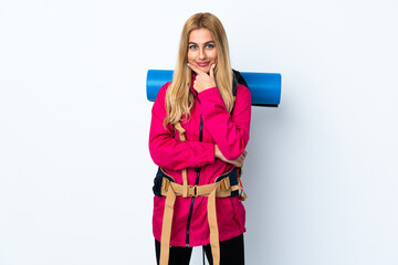 Young mountaineer woman with a big backpack over isolated white background laughing