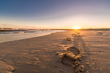 sunset at the beach with footprints on the sand