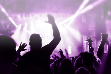 Crowd at a music concert, audience raising hands up, toned