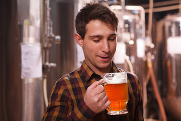 Excited brewer tasting freshly brewed beer at his microbrewery