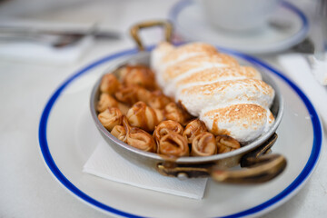 Plate of delicious mini pancakes with meringue cream, powdered sugar and caramel at the restaurant. Closeup view