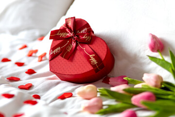 Red gift box in the form of a heart on the bed. Valentine's Day