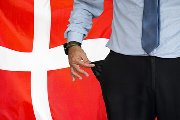 Man turns up his trouser pocket on the background of the Denmark flag