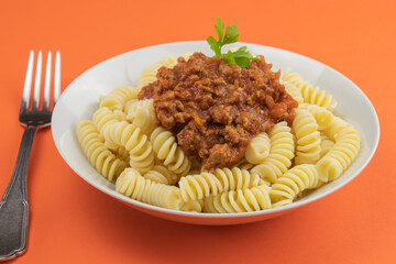 plate of pasta bolognese on an orange background