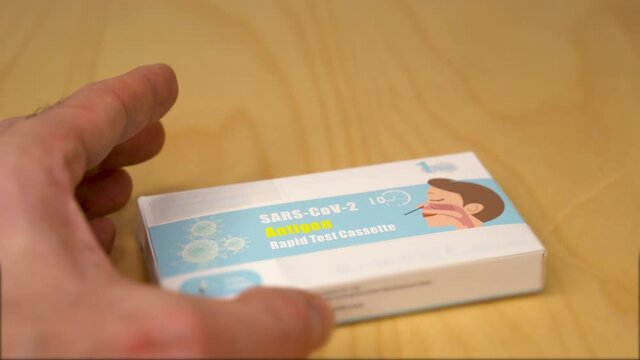 Man holding a box of commercial rapid antigen test