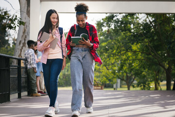 Fototapeta premium Girl student walk with friend and looking book at school park