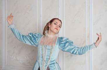 Beautiful young woman in medieval style blue dress with hands up
