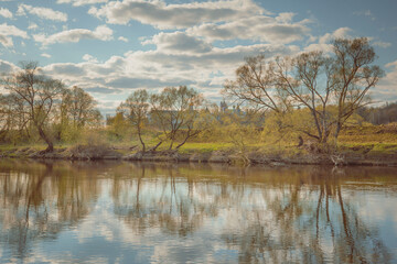 Spring landscape with river, old monastery, trees and clouds