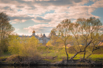 Spring landscape with river, old monastery, trees and clouds