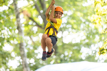 Teenage girl goes on hinged trail in extreme rope Park in summer forest. High-altitude climbing...