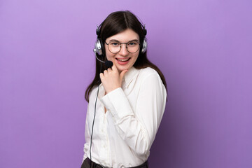 Telemarketer Russian woman working with a headset isolated on purple background with glasses and smiling